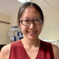 A smiling Miss Christine Gan wearing a red top and glasses.